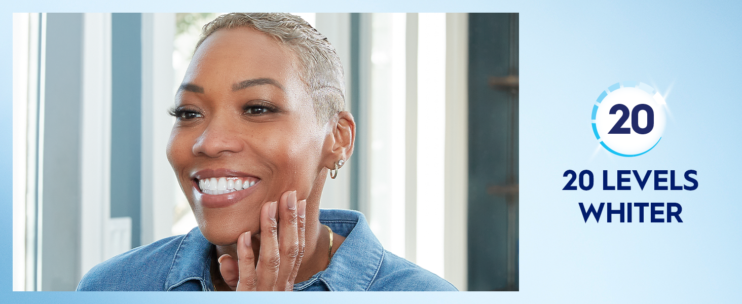 A woman smiles bright into mirror showing off her white smile. Claim reads: 20 levels whiter.