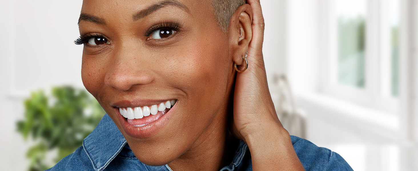 Woman holds hand behind ear and smiles showing off her bright smile after using Crest 3DWhitestrips.