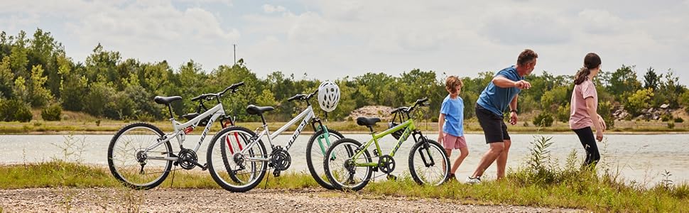 Family of 4 at park skipping stones with Huffy Stone Mountain bikes in foreground