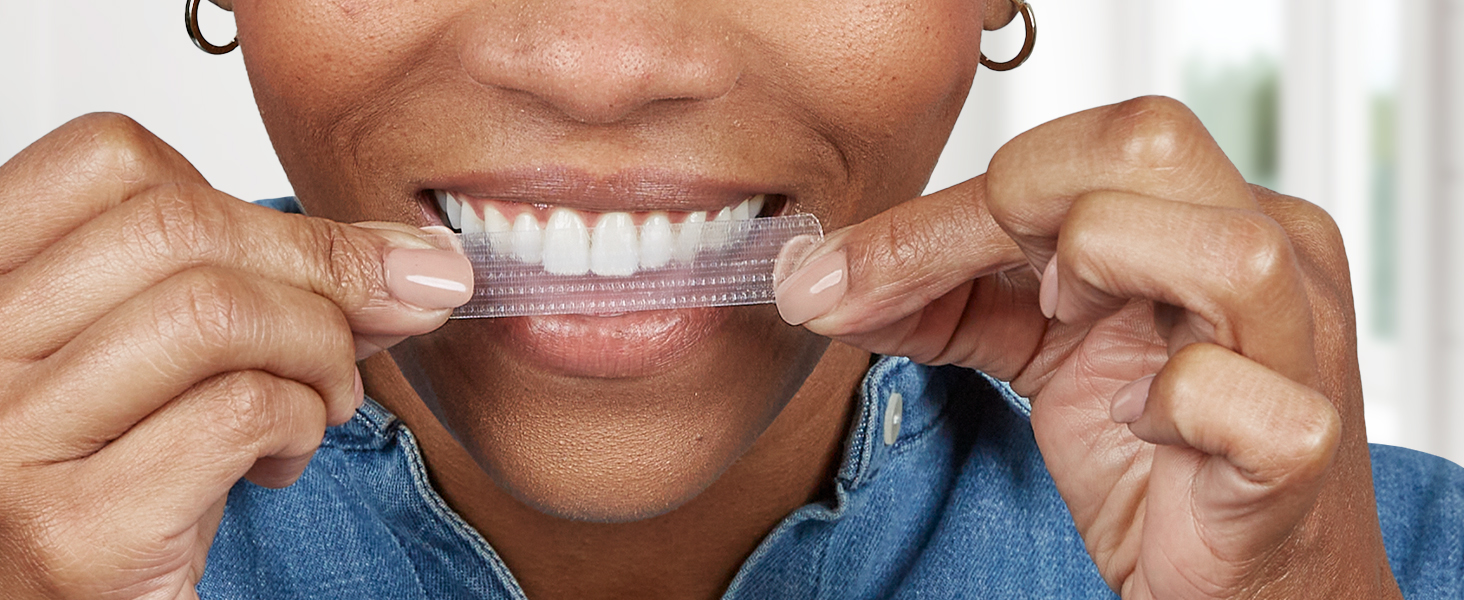 Up-close image of woman applying Crest 3DWhitestrips to the front of her teeth.